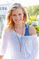 A young blonde woman wearing a blue top and a white net jumper