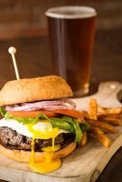 A burger with a fried egg, chips and beer