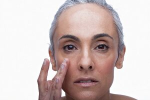 An older woman touching her cheek