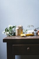 An arrangement of ingredients in storage jars, bananas and eggs on a table