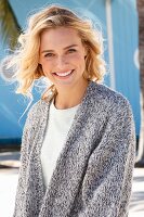 A young blonde woman in a white top and mottled grey knitted cardigan