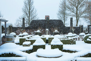 Formal gestalteter Garten im Winter, mit Buchsbaumhecken unter Schnee bedeckt