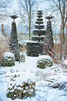 Winterlicher Garten mit schneebedeckten Formschnitt-Bäumen