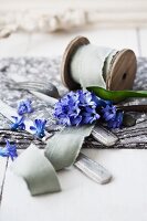 Ribbon on wooden reel, cutlery and hyacinths on table