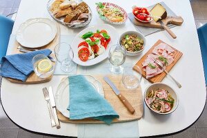 A set table for evening tea with salads, bread, cold cuts and cheese