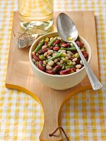 Bean salad in a bowl on a wooden board