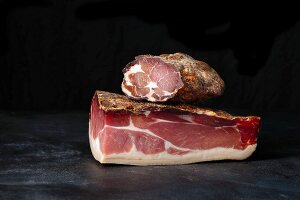 Tyrolean ham and bacon in front of a dark background