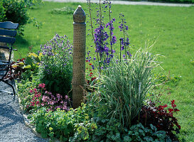 Clay column as a water feature in a flowerbed