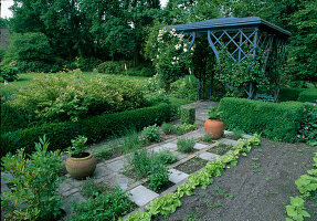 Small herb garden and salad beds next to box hedges in front of small pavilion