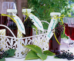 Flaschen mit Saft von Beeren von Sambucus (Holunder) auf Metalltablett