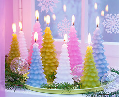 Pastel colored candles in fir tree shape on a light green tray by the window