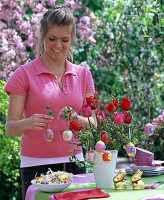 Frau schmückt Osterstrauß aus Tulipa (Tulpen) und Corylus (Haselnuß)