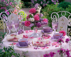 Etagere mit Rosa (Rosen) und Syringa (Flieder) auf gedecktem Teetisch