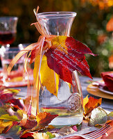 Leaves, apple, table deco and carafe with autumn Parthenocissus leaves