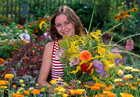 Young woman picking flowers for a bouquet in a cottage garden