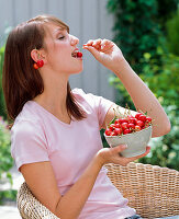 Young woman eating Prunus avium (sweet cherries)