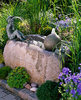 Stone trough with ball and flute player as a water feature