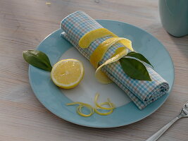 Citrus limon (Zitrone), Scheibe, Blätter, Schale und Zesten als Serviettendeko
