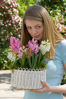 Junge Frau schnuppert an Hyacinthus (Hyazinthen) in weißem Korb