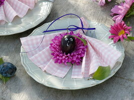 Napkin decoration of pink summer aster blossoms with plums