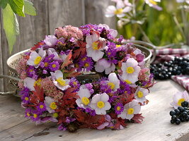 Wreath of autumn anemones, asters, sedum and beaked leaves