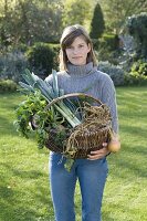 Young woman holding wicker basket with vegetables