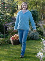 Young woman carrying a wicker basket with apples