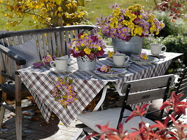 Herbstliche Tischdeko mit Herbstchrysanthemen und Heuchera-Blättern