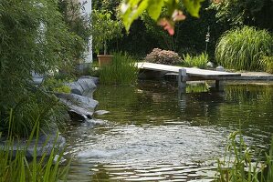 Schwimmteich mit Holzsteg eingefaßt mit Granit-Blöcken