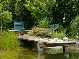 Swimming pond with wooden pier bordered with granite blocks