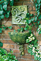 Wasserspiel: An der Wand montierter Keramik-Schlangenbrunnen mit passender Schale und Halterung.