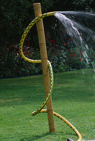 Water Feature: Water SERPENT Made From Yellow Hose TIED with TWINE TO BAMBOO POLE IN LAWN. Designer: Clare MATTHEWS