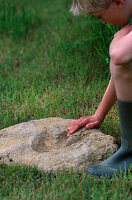 Dinosaurier-Fußabdrücke: Junge berührt Zementform des Fußabdrucks
