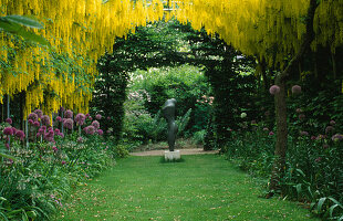 Der Goldregenbogen im Frühling mit Allium und der Skulptur 'Mutter und Kind'