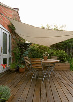 Ein Platz zum Sitzen: Holztisch und Stühle auf der Terrasse mit Schatten spendendem Vordach