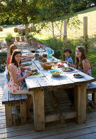 Clare MATTHEWS Garden, DEVON. Clare AND FAMILY SIT DOWN TO an Al Fresco LUNCH at THE TABLE. OUTDOOR DINING. Food, A PLACE TO SIT, EATING