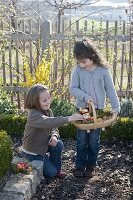 Mädchen suchen Ostereier im Bauerngarten