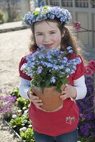 Mädchen mit Myosotis (Vergißmeinnicht) im Topf und als Kranz