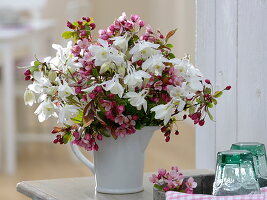 Strauß aus Malus (Zierapfelblüten) und Aquilegia (Akelei) in weißem Krug