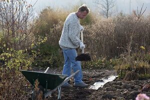 Mann bringt Kompost im Garten aus