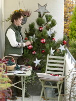 Frau schmückt Pinus (Kiefer) weihnachtlich