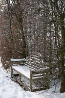 Verschneite Holzbank in Nische von Hecke aus Carpinus