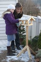 Mutter und Tochter befüllen ein Vogelfutterhaus