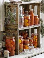 Eingemachte Tomaten, Peperoni, Essig und Kräuter in selbstgebautem Regal