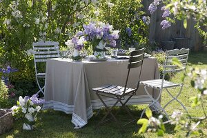 Flieder-Tischdeko im Garten vor Fliederbüschen