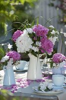 Rosa-weiße Pfingstrosen-Tischdeko auf der Terrasse