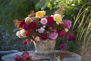 Bouquet of mixed pinks (roses) and rose hips in rustic vase