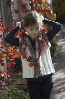 Girl with autumn necklace made of purple string, physalis (lanterns), pink