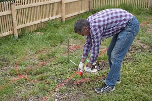 Gartenplanung : Mann zeichnet Gartenmitte mit rotem Farbpulver an