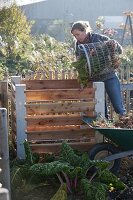 Frau schüttet Gartenabfälle in den Kompost-Behälter